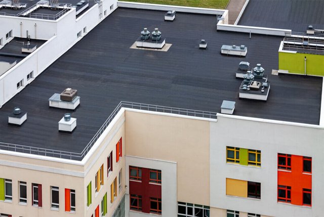 Flat black roof on a colorful commercial building by roofing contractors.